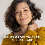An older woman smiling with her hand on her neck. Text on image reads, "Helps grow thicker, fuller hair*"