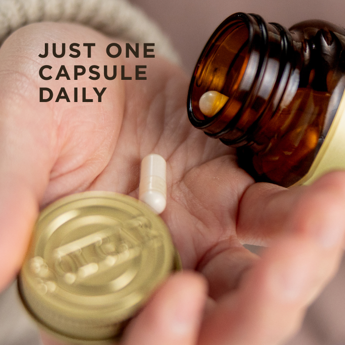 One white capsule of Solgar Cellulite Fighter, being poured from an amber glass bottle into a hand. Text on the image reads, "Just one capsule daily"