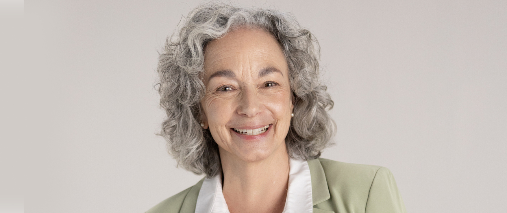 A healthy, happy older woman in a green jacket smiling at the camera