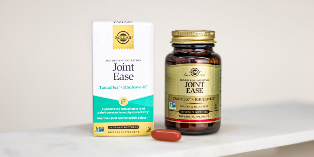 A box and bottle of Solgar Joint Ease capsules on a white marble countertop. One red capsule is sitting outside the bottle.  