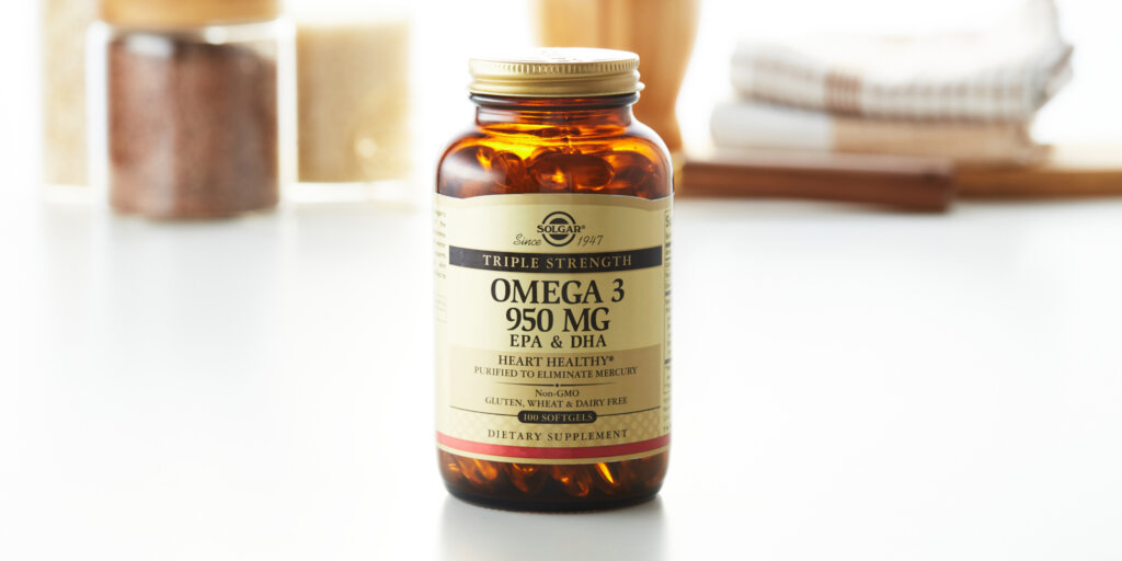 An amber glass bottle of Solgar Triple Strength Omega 3 softgels on a clean white kitchen countertop.