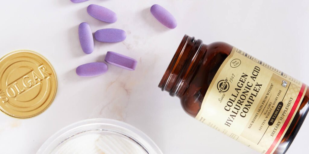 a amber glass bottle with gold label laying on its side spilling out purple tablets on a marble background 