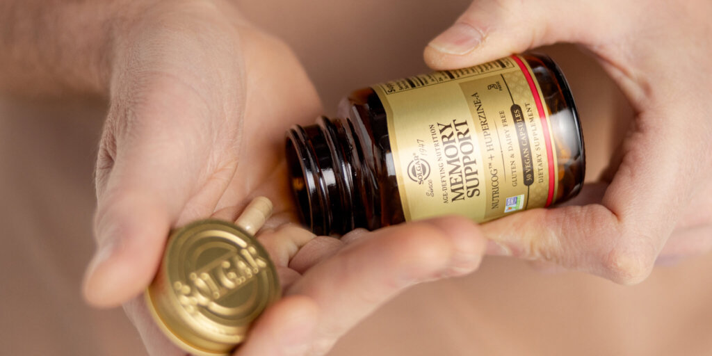 hands holding a amber glass bottle with a capsule spilling out