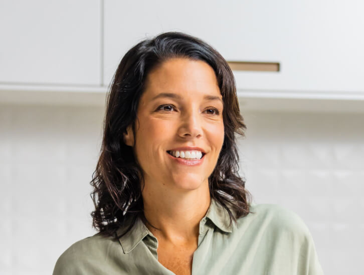 brunette woman in a white kitchen smiling